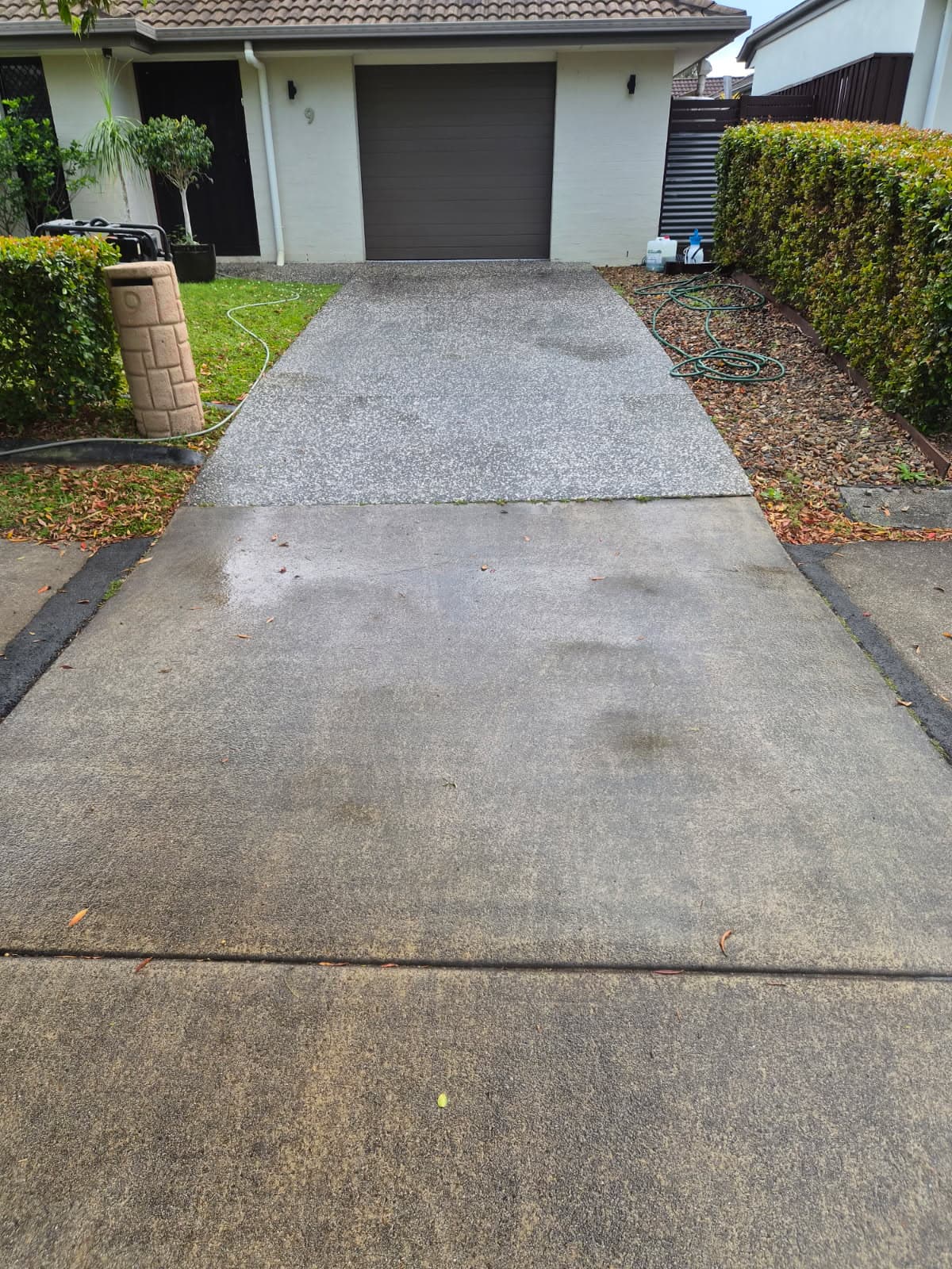 The same driveway after pressure cleaning, with the concrete restored to an even, clean finish