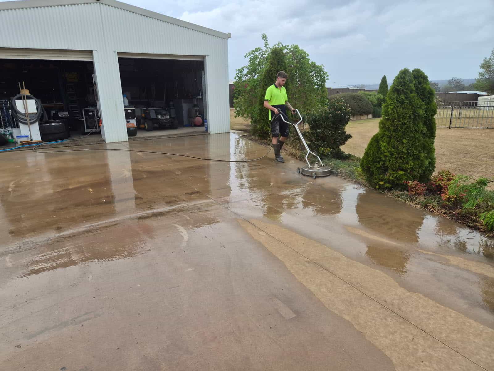 Darling Downs Epoxy technician pressure cleaning a concrete shed slab with a surface cleaner